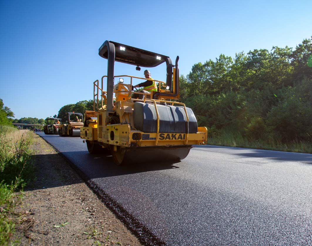 construction working smoothing asphalt with a roadroller on job site