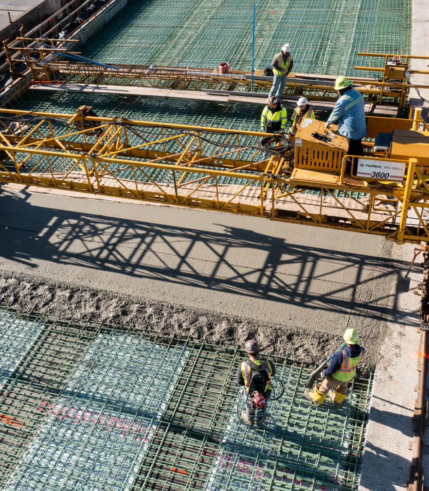 construction workers laying concrete over rebar