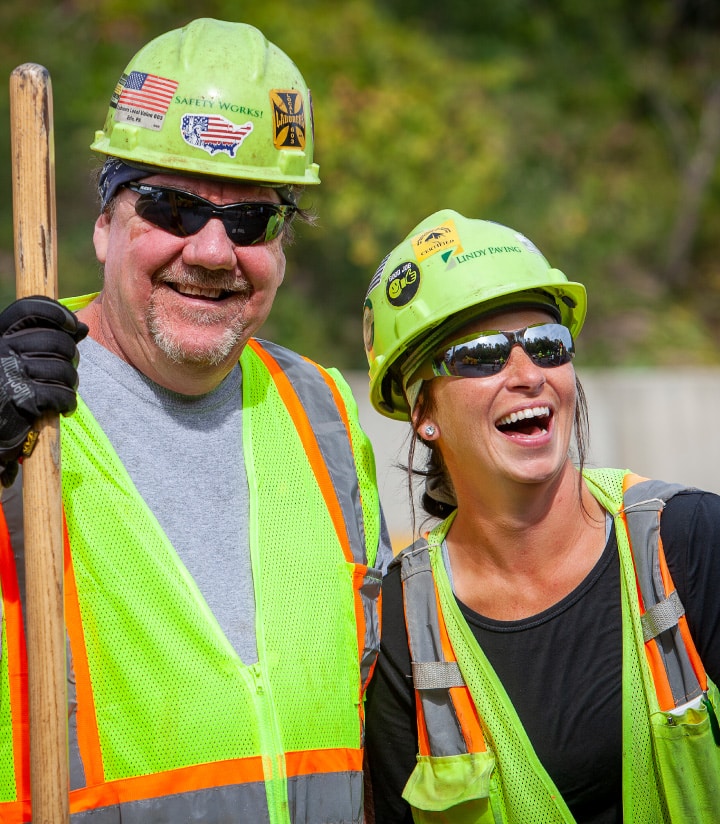 two workers smiling and laughing together on a job site