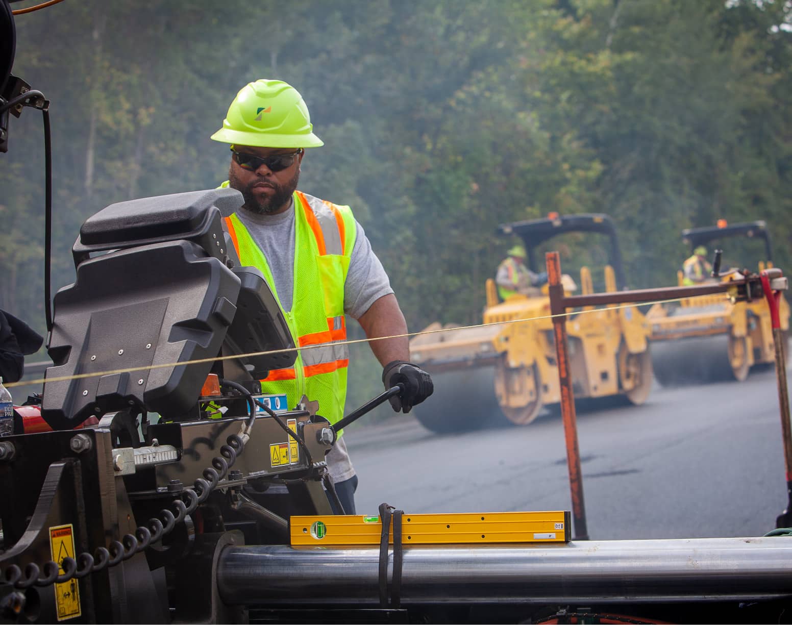 construction worker manning an asphalt paver on a job site 