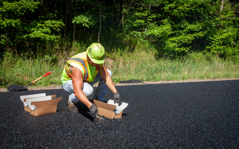 construction worker taking a sample of asphalt 